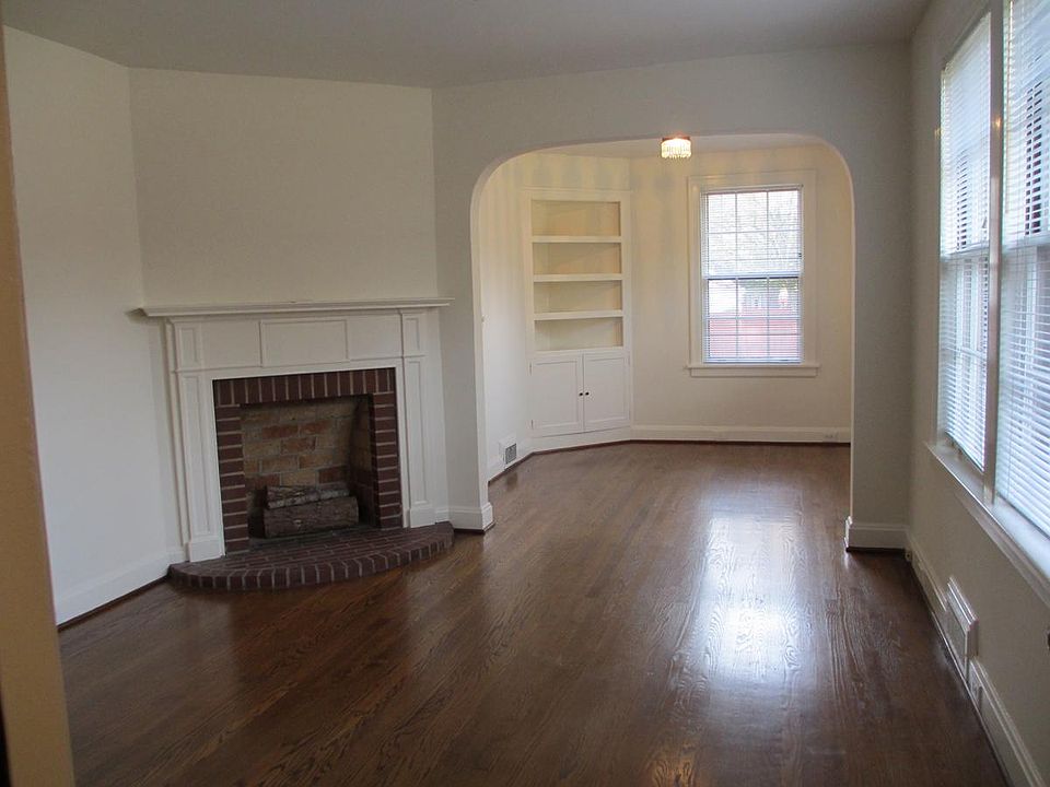 Living room and dining room with built-in cabinet viewed from apartment front door. Refinished hardwood floors.