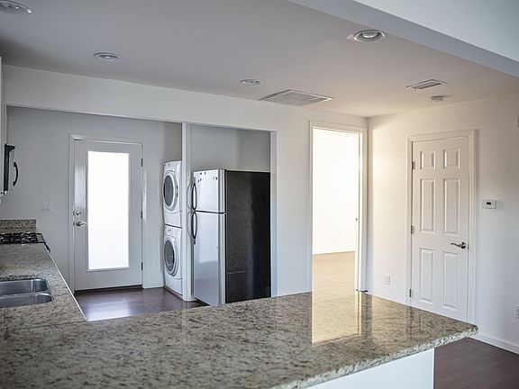 Kitchen, fridge, washer/dryer and back bedroom