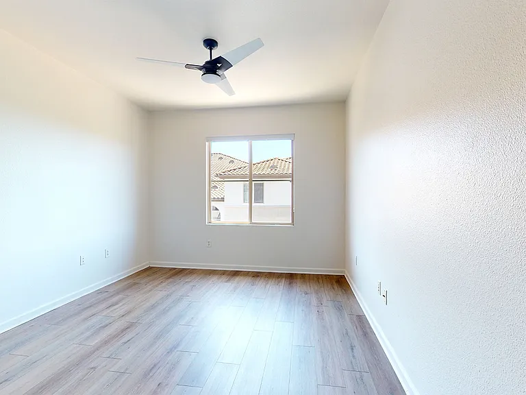 Spacious apartment bedroom with wood-style flooring.