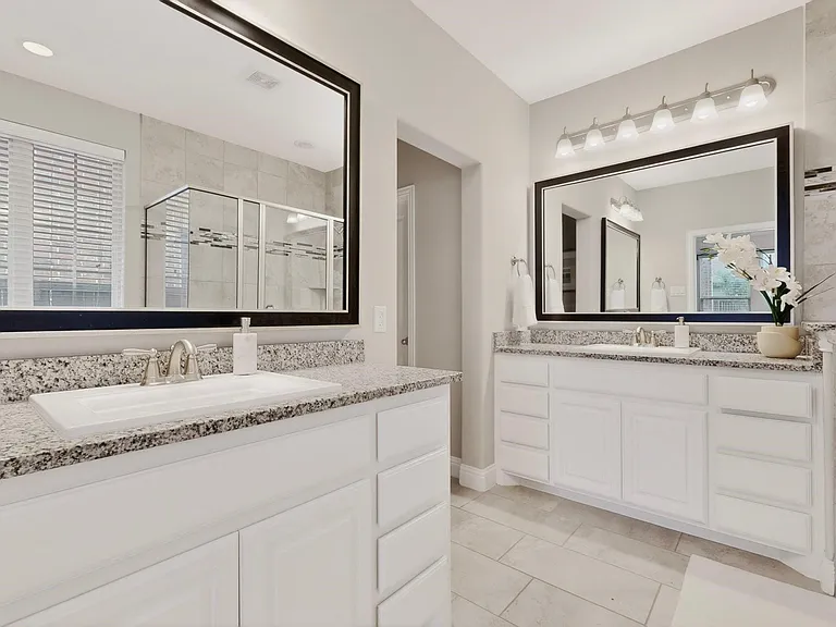 A bright primary bathroom featuring separate vanities and a large mirror for each, reflecting the space.