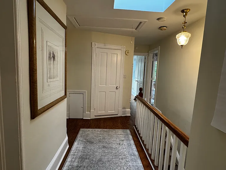 Upstairs hallway looking toward back of house (closed door is guest bathroom; straight back from stairs is 4th bedroom/ laundry; door to right is primary bedroom).