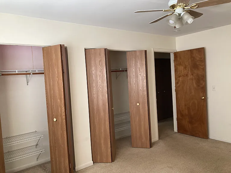 Master bedroom with full wall of closets and ceiling fan with lights