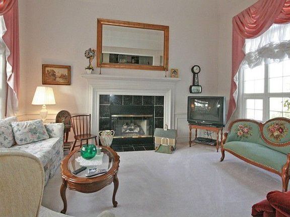 A bright formal living room with two sides of windows and a gas fireplace, just of the main entry.