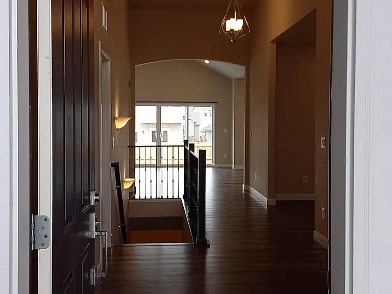 Looking through the front door from the porch, past the dining/living room, through the Great-room, out the double-wide glass patio door.