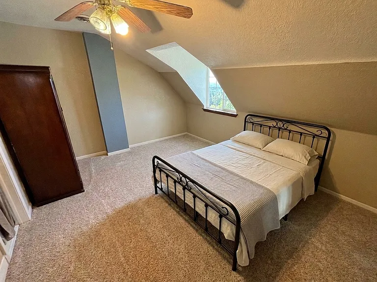 Upper-level bedroom featuring a comfortable queen bed, dedicated clothing storage, and a private en-suite bathroom with a shower.