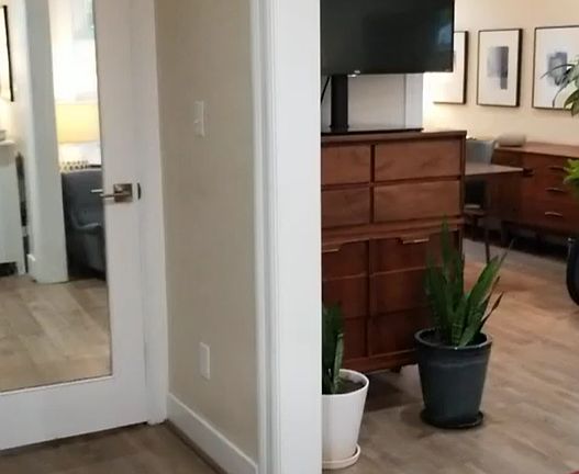 View from foyer into living room and dining room on right. Hall closet, pantry behind mirrored door.