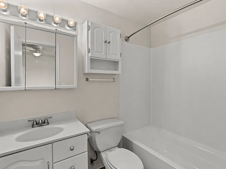 Clean and bright bathroom featuring a full tub, spacious vanity, and extra cabinet storage. Clean and bright bathroom featuring a full tub, spacious vanity, and extra cabinet storage.