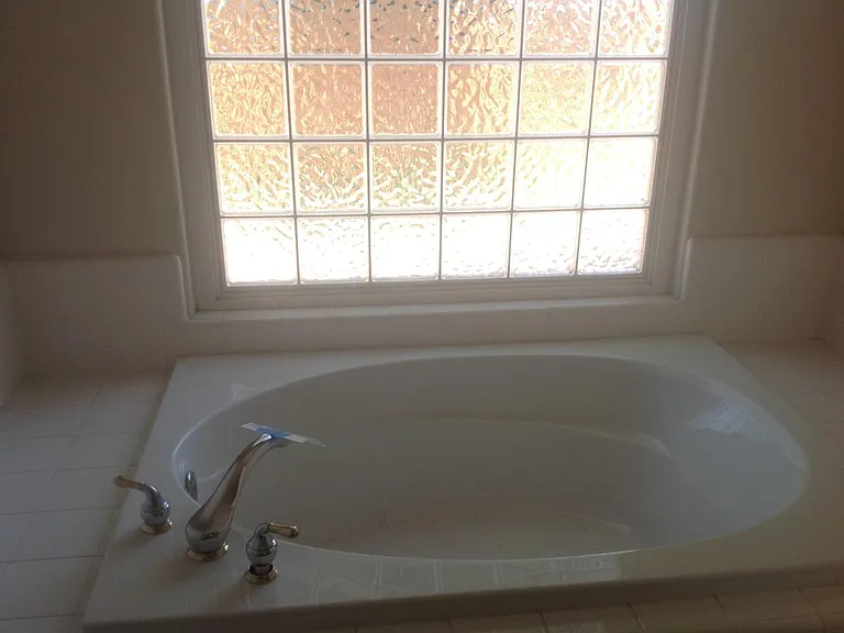 Master bath with dual sinks, soaker tub, and separate toilet
