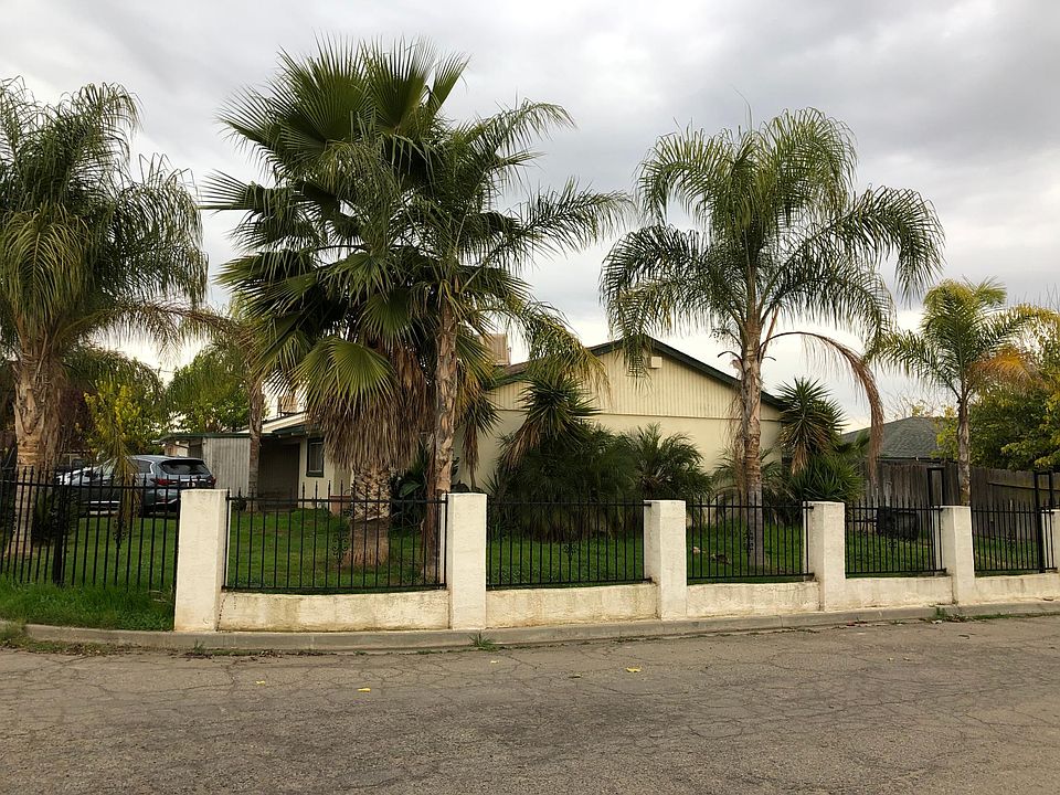 Side view of the house fully inclosed by a rod iron gate
