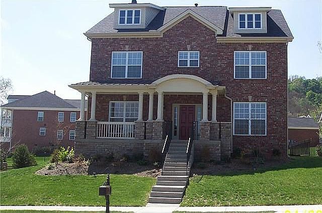 Rocking chair front porch with view of lake, fountain, treed lined blvd.