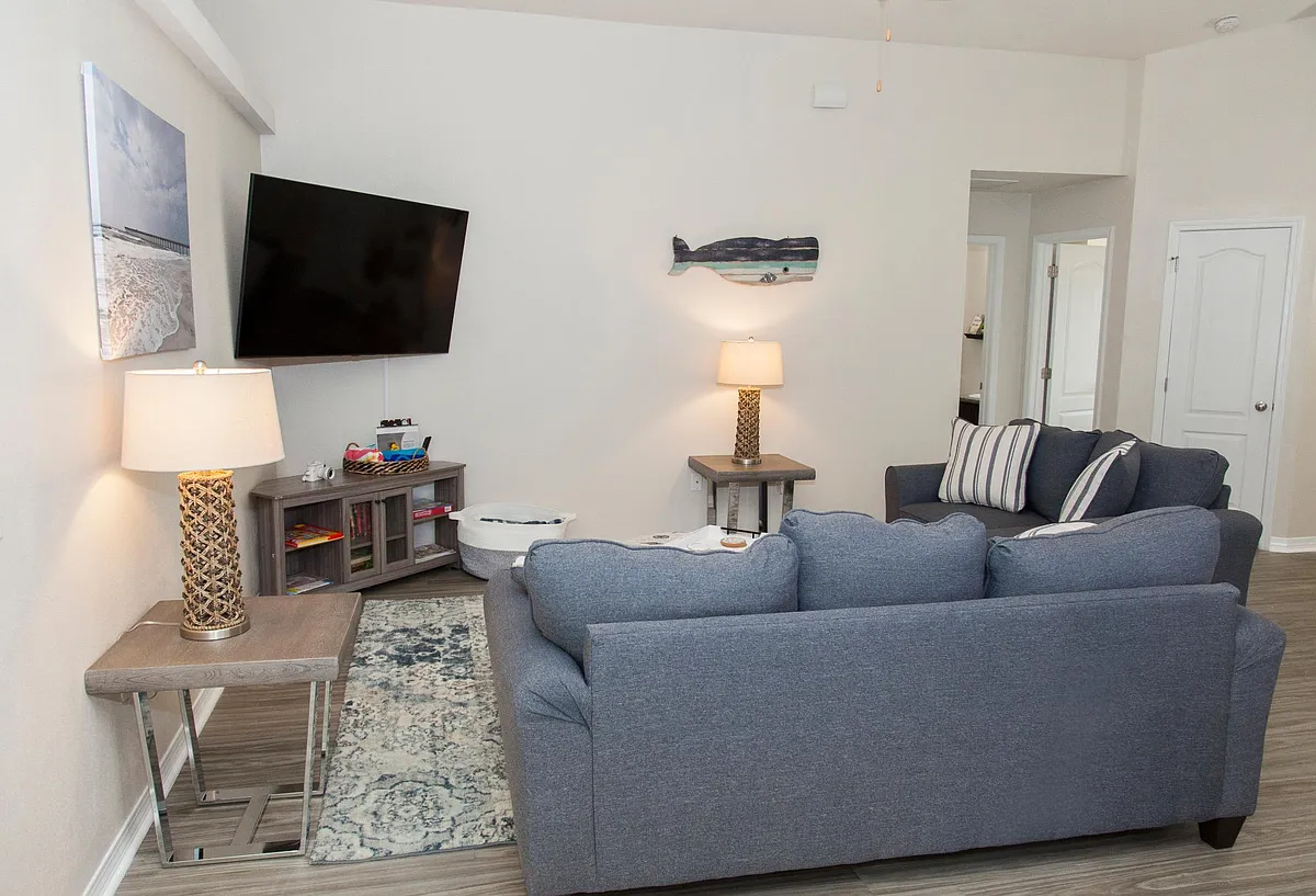 Relax and unwind in our cozy family room, the perfect spot to gather and enjoy. With a large HDTV for movie nights, comfy seating, and a collection of kids' books, it's ideal for both adults and children to relax and enjoy downtime together. - 8378 Island Dr