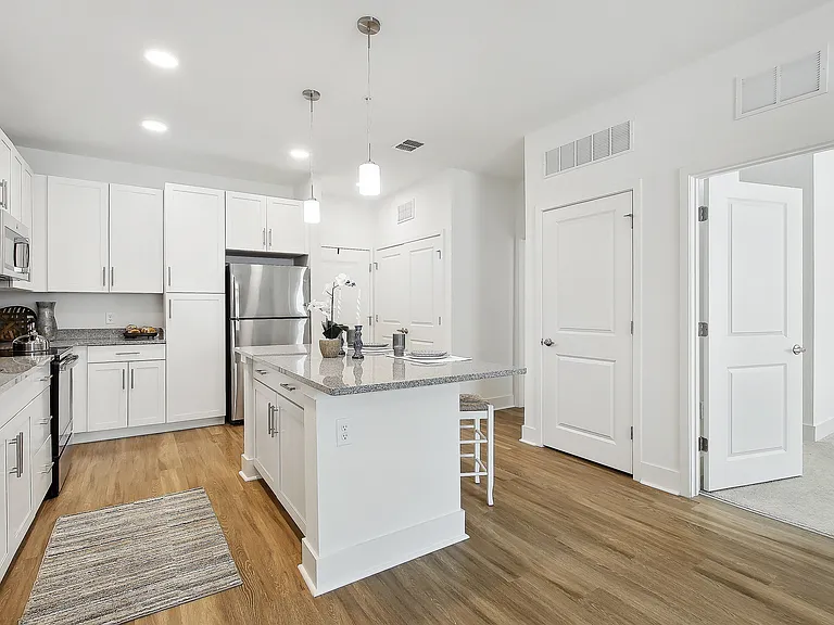Modern kitchen showcasing sleek white cabinetry, stainless steel appliances, and a stylish central island with pendant lighting.