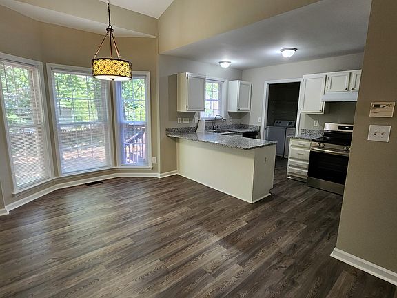 Dining area with bay window with kitchen counter and kitchen in background.