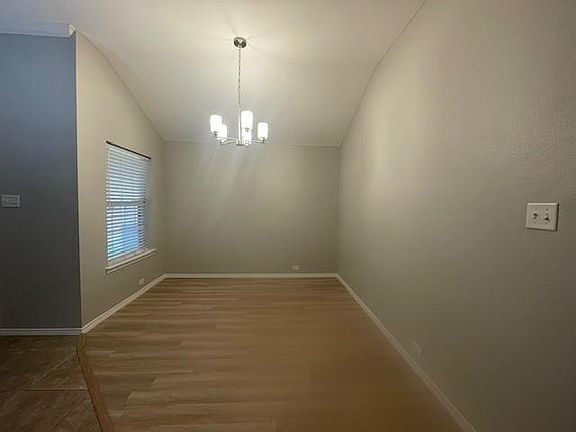 Unfurnished dining area with lofted ceiling, a chandelier, and wood finished floors