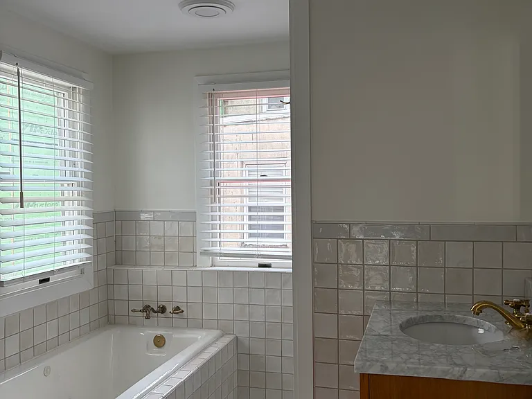 Main bathroom, renovated in 2024, includes vanity, separate jetted tub, shower stall, and unique cabinetry.