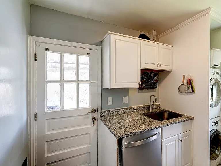 Dishwasher, sink, additional cabinetry & exit to driveway
