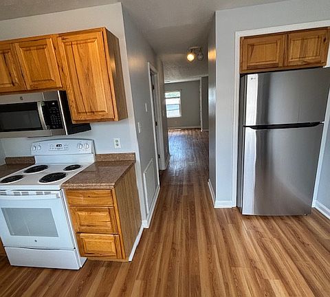 Kitchen looking from deck door also down hall past laundry room towards living room. New stainless steel microwave and fridge.