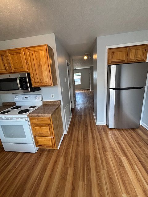 Kitchen looking from deck door also down hall past laundry room towards living room. New stainless steel microwave and fridge.