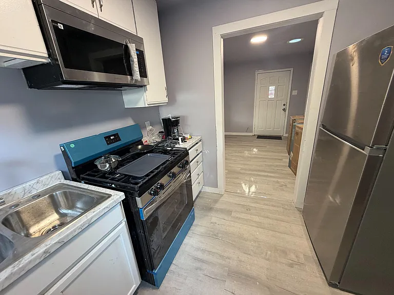 Galley kitchen with stainless fridge, gas range, microwave, and ample cabinetry plus a full sink and counter prep space.