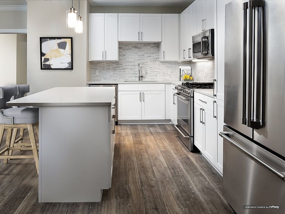 Signature Collection kitchen with white cabinetry, light grey quartz countertops, white marbled subway tile backsplash, stainless steel appliances, and hard surface flooring