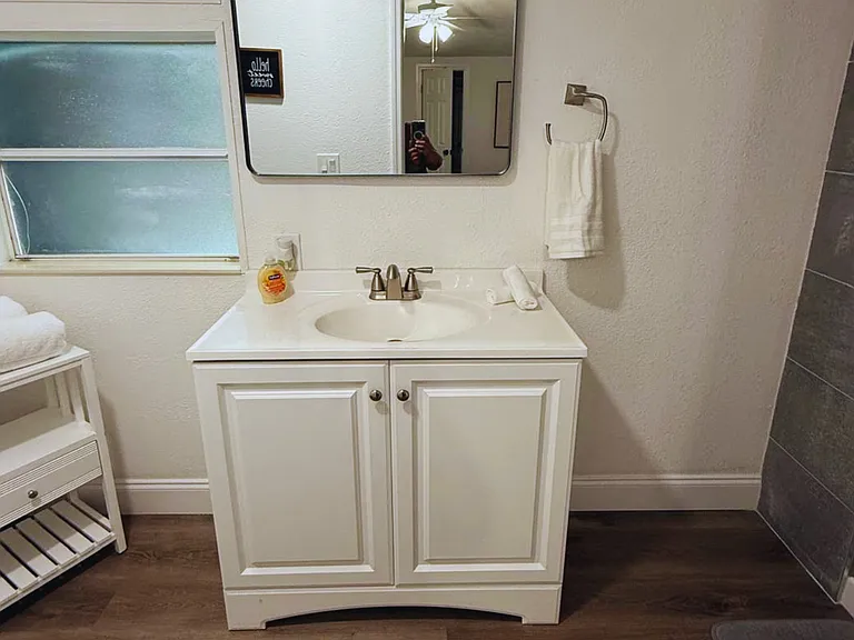 Spotless bathroom featuring a mirror, cabinetry, towels and a bright window.