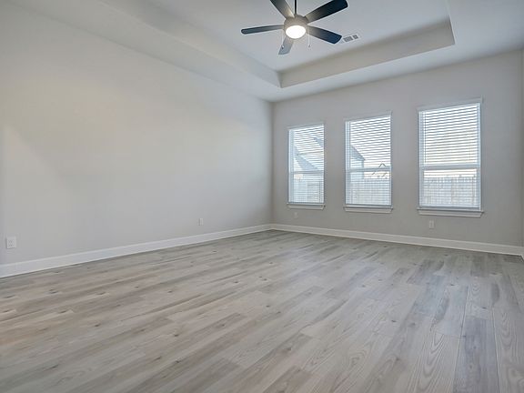 Master bedroom with three large windows that create a bright, open room.