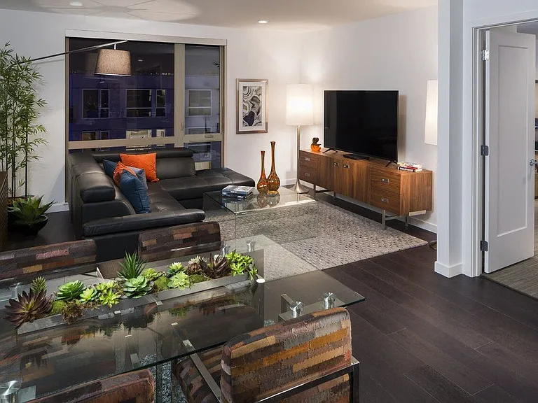 Living Space with Wall-Mounted TV, Dining Table, and Bedroom Access