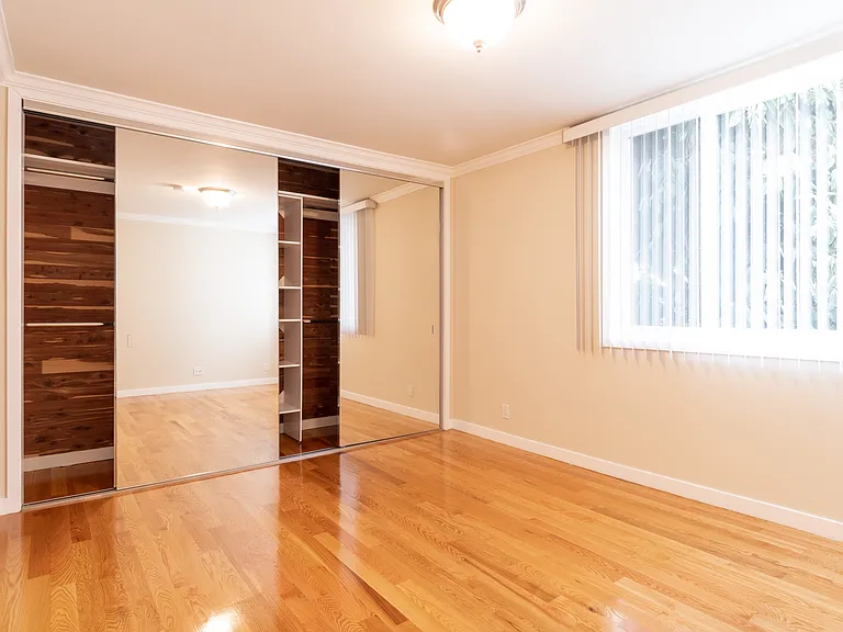 SECOND BEDROOM HAS LARGE TRIPLE MIRRORED CLOSET WITH CUSTOM SHELVING AND CEDER LINED