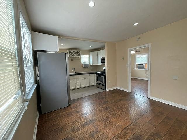 View of the kitchen from the corner of the living room. Bedroom door is on in the middle of the photo
