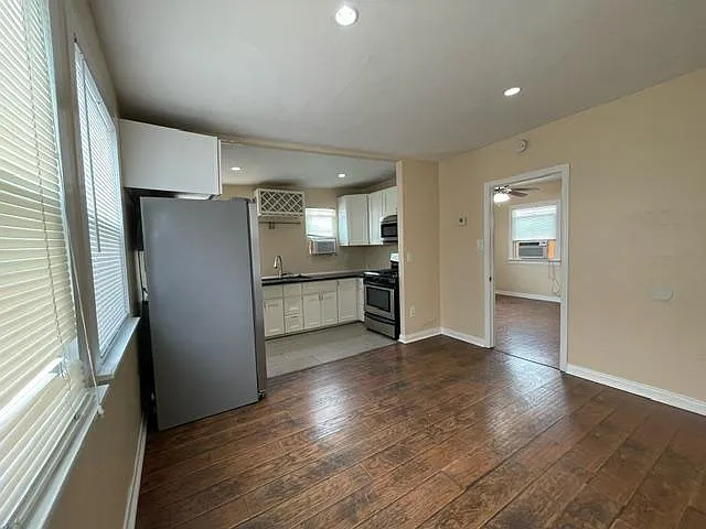 View of the kitchen from the corner of the living room. Bedroom door is on in the middle of the photo