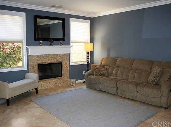 Large open living room with stone fireplace. The travertine floors flow into the main rooms downstai