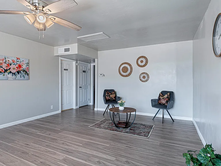 Open living area with durable wood-look flooring, ceiling fan, and space for a seating or work-from-home setup.