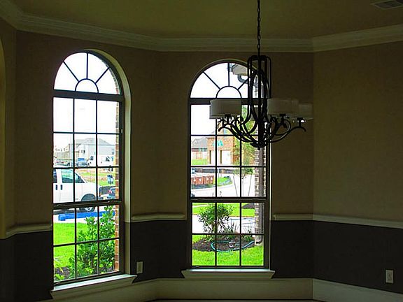 Beautiful formal dining room! Note the arched windows, chair rail, crown molding, high base boards, and 2 toned wall color and oil rubbed bronze fixture!