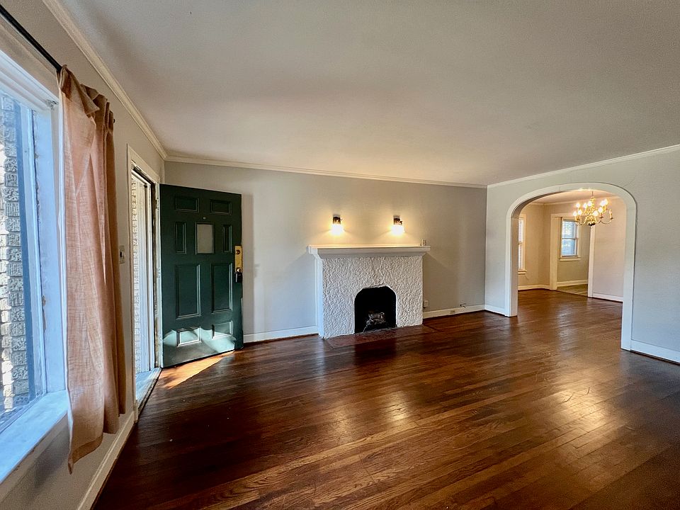 6015 Ross Avenue living room with large pane front window, decorative fireplace & arched entry to the dining room.