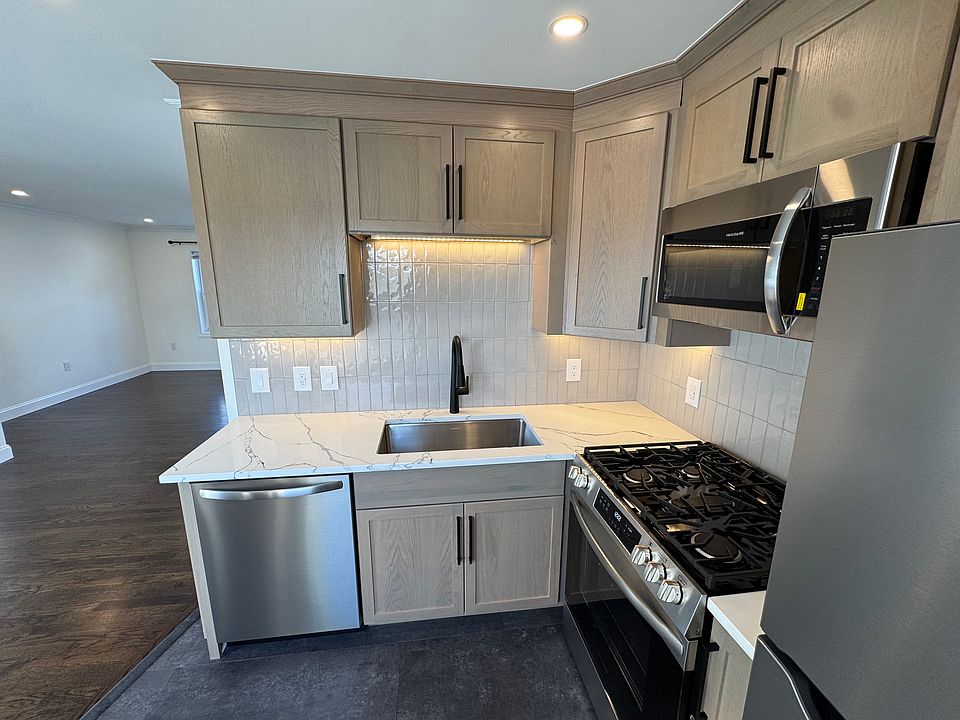Brand new kitchen with quartz counters, large sink, under cabinet lighting and new appliances.