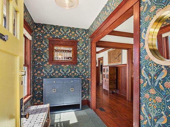 Entrance with stunning wallpaper, bench seating, space for shoes and last look mirror.