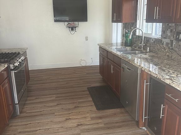 remodeled kitchen with stove and refrigerator with wine refrigerator and mounted TV