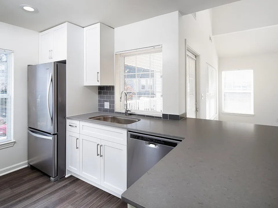 Kitchen with gray quartz countertops, tile backsplash, stainless steel appliances, and upgraded fixtures