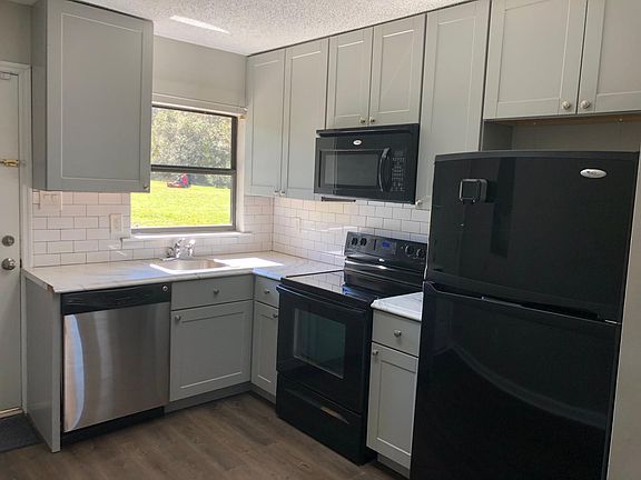 Open layout kitchen with new subway tile backsplash, new white 42" shaker cabinets, with: refrigerator, dishwasher, electric range/oven, and over the range vented microwave. Access to private concrete patio, 1.5+ grounds with storage shed.