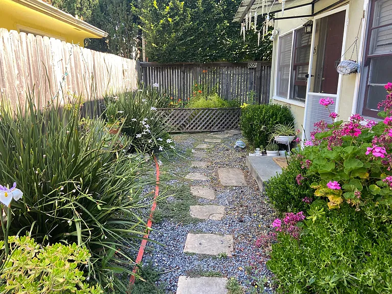 Walkway to the back of the property where your front door is. Space for your own planting.