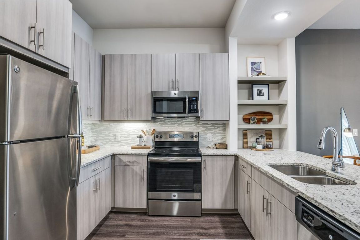 Gray finish package kitchen with speckled granite countertop, stainless steel appliances, and hard surface flooring.
