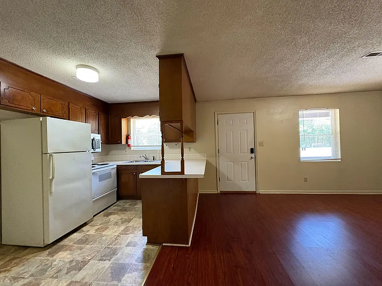 Open kitchen with breakfast bar, ample upper cabinetry, and a full appliance set, flowing into the adjacent living area.