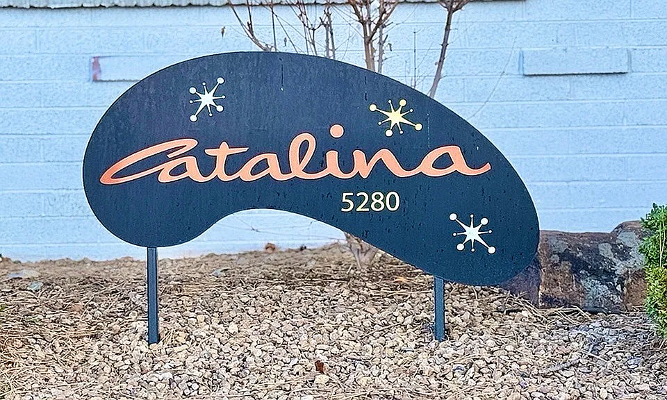 Chic and inviting apartment sign reading 'Catalina 5280' with decorative graphic accents, set amidst a serene stone landscape.