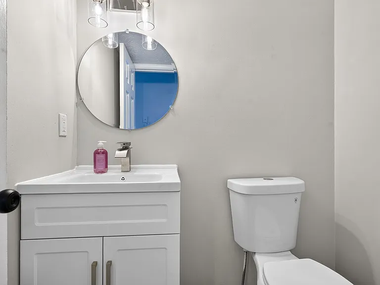 Bathroom vanity with cabinet storage, round mirror, and updated fixtures for convenient daily routines.