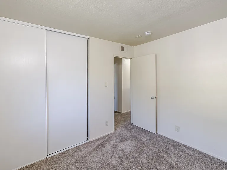 Bedroom B features plush carpeting and a spacious sliding-door closet for easy organization.