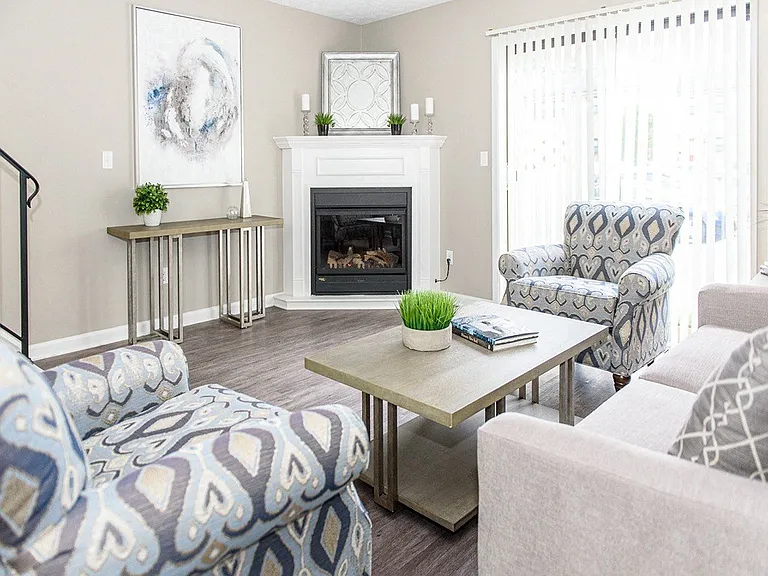 Open layout living/dining area with fireplace, sliding doors to private patio, & staircase to second floor (fireplaces in select apartment homes only)
