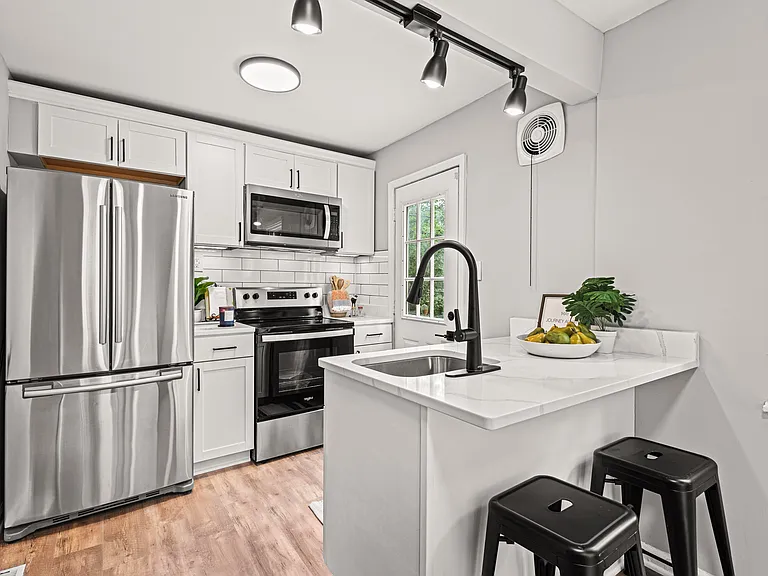 Renovated kitchen with quarts countertop and bar stool where you can do additional work.