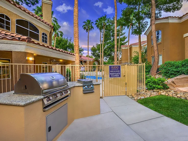 Gas grilling station with granite counters and pool area in background.