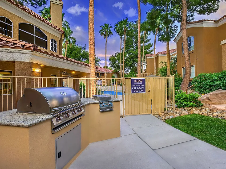 Gas grilling station with granite counters and pool area in background.