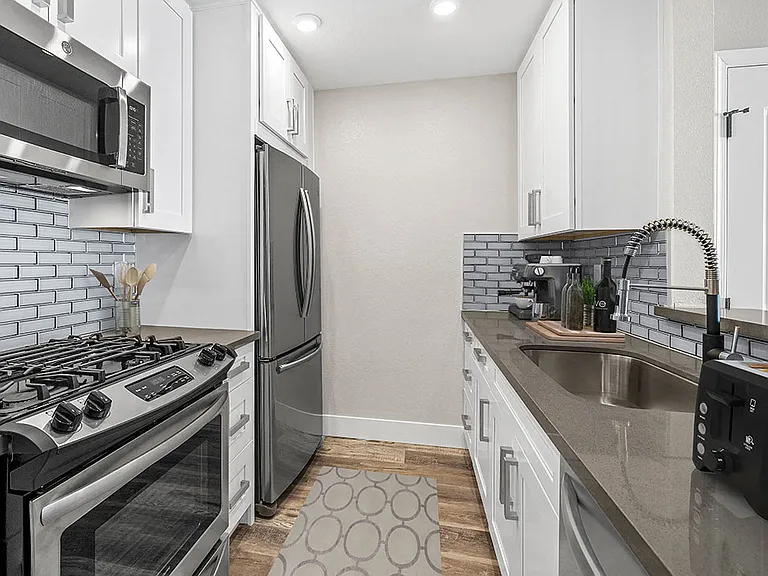 Blue tiled kitchen with stainless steel fridge, oven, and fixtures.
